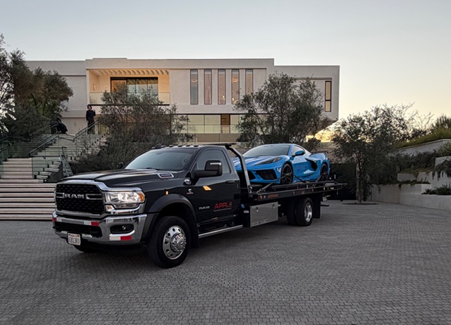 C8 Corvette on flatbed in front of mansion at sunset